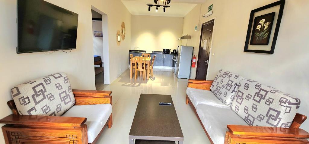a living room with two couches and a table at Number 7, 2nd floor, Pebble Bay Apartments with Garden View in Grand Baie