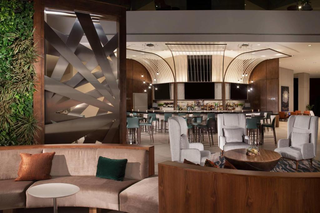 un vestíbulo con un bar con sillas y una mesa en The Westin Dallas Park Central, en Dallas