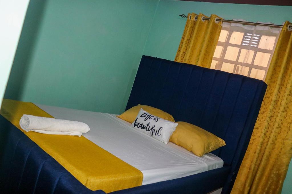 1 cama con almohadas amarillas y blancas y ventana en Trendy Homes - 2 Bedroom, en Bungoma