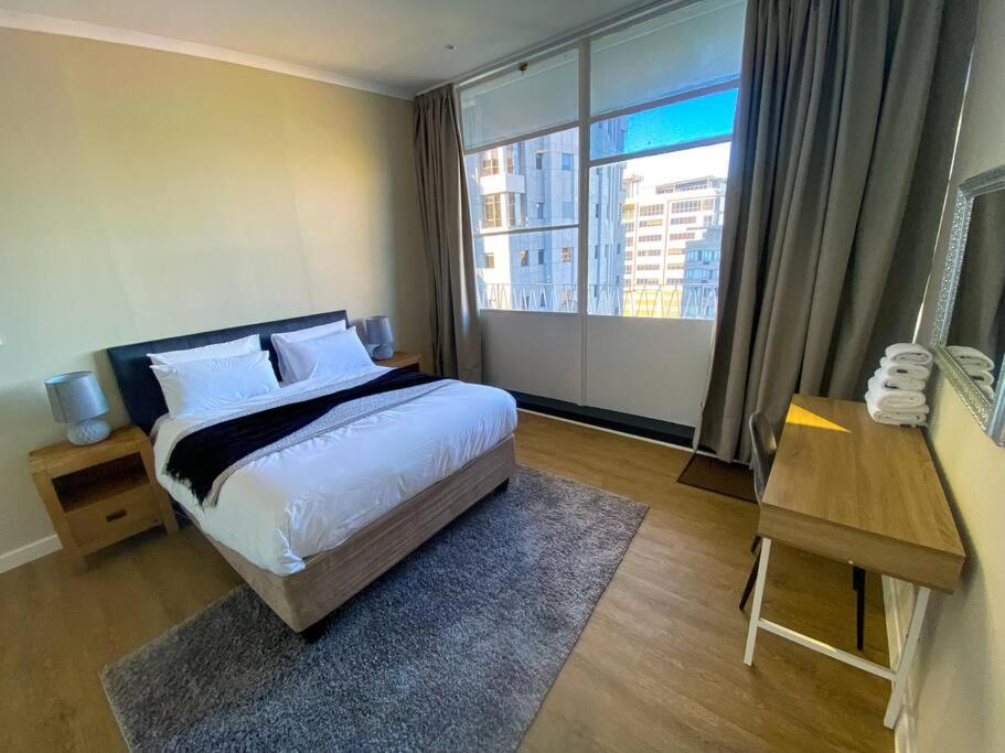 a bedroom with a bed and a desk and a window at Spacious 2-bed unit no-powercuts in Cape Town