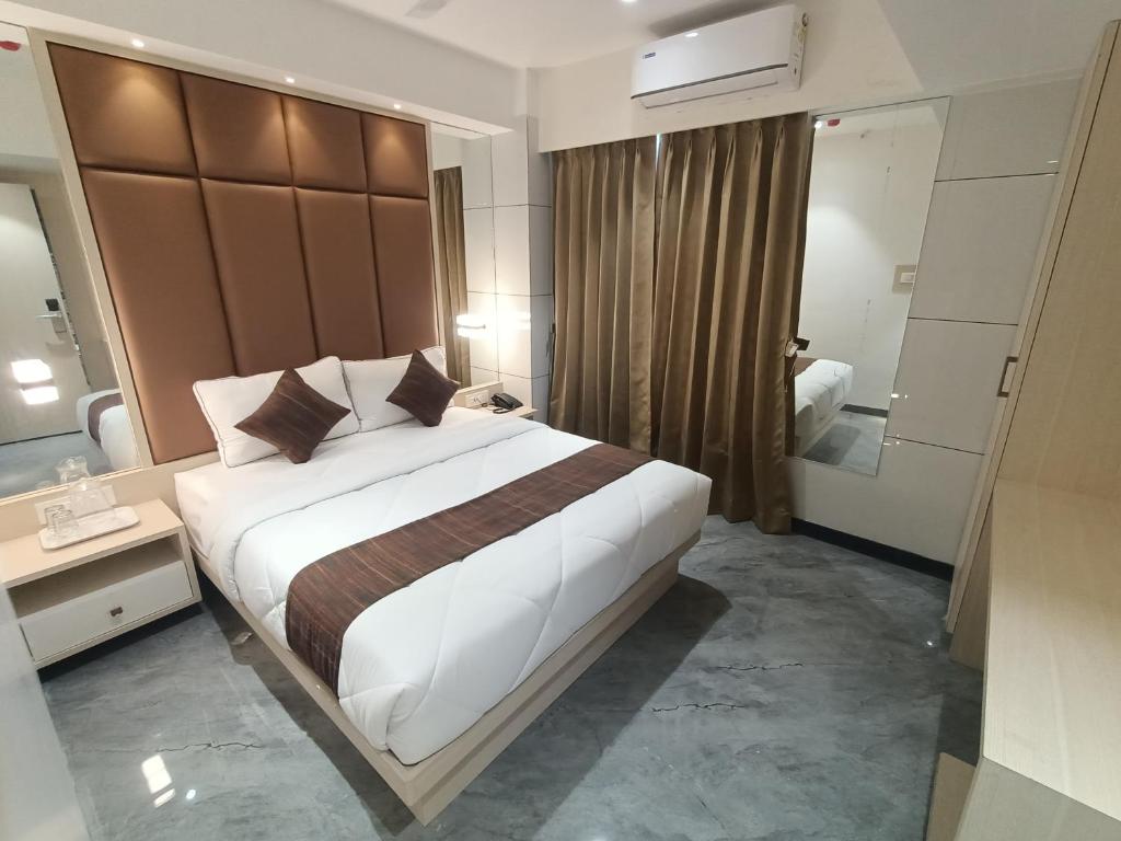 a hotel room with a large bed and a bathroom at Hotel Pearl Residency in Thane