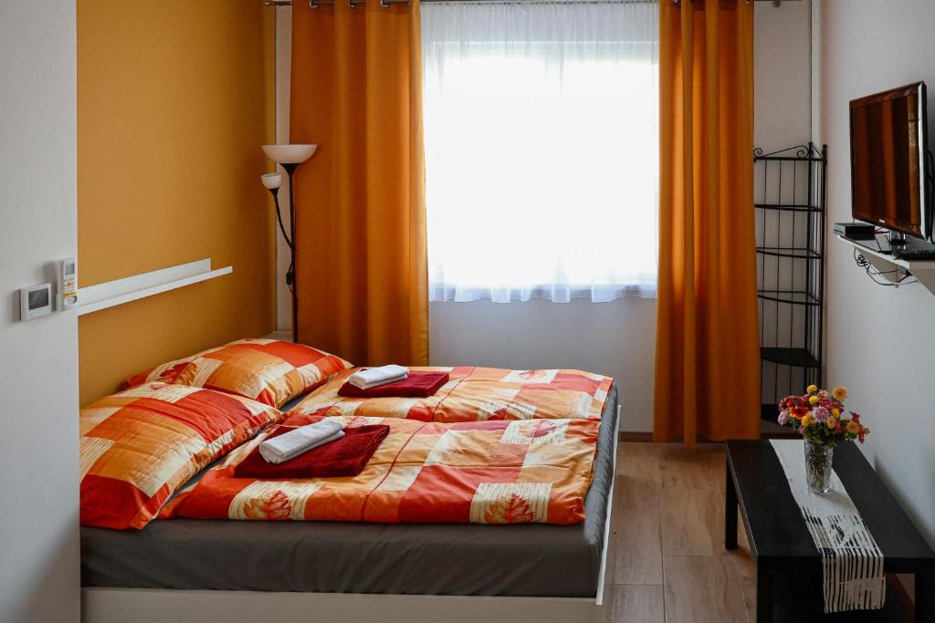 una camera da letto con un letto con tende arancioni e una finestra di Apartman Pollux a Nesvady