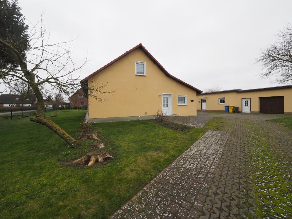 a yellow house with a tree next to a brick road at Ferienwohnung Matersen 