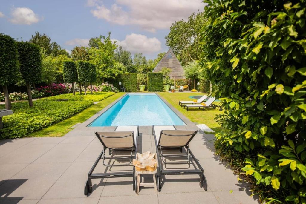 una piscina con due sedie e un tavolo accanto a una piscina di Fabulous 4 Bedroom Villa (KS-10) a Eindhoven