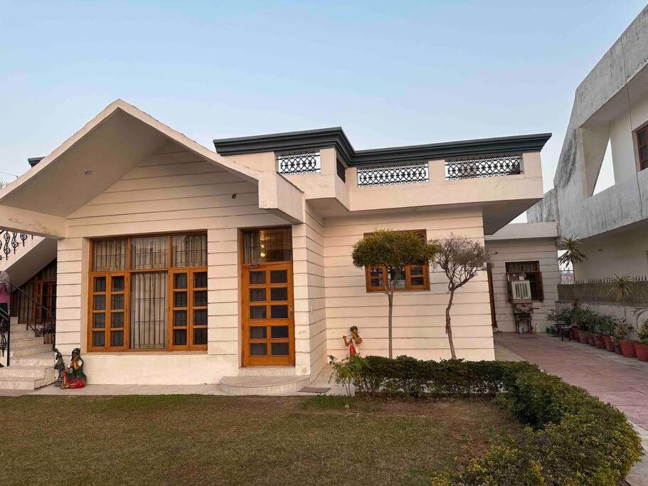 昌迪加爾的住宿－Anand Nilaya (2.5 km from Sukhna Lake, Chd)，一间白色的小房子,设有棕色的门