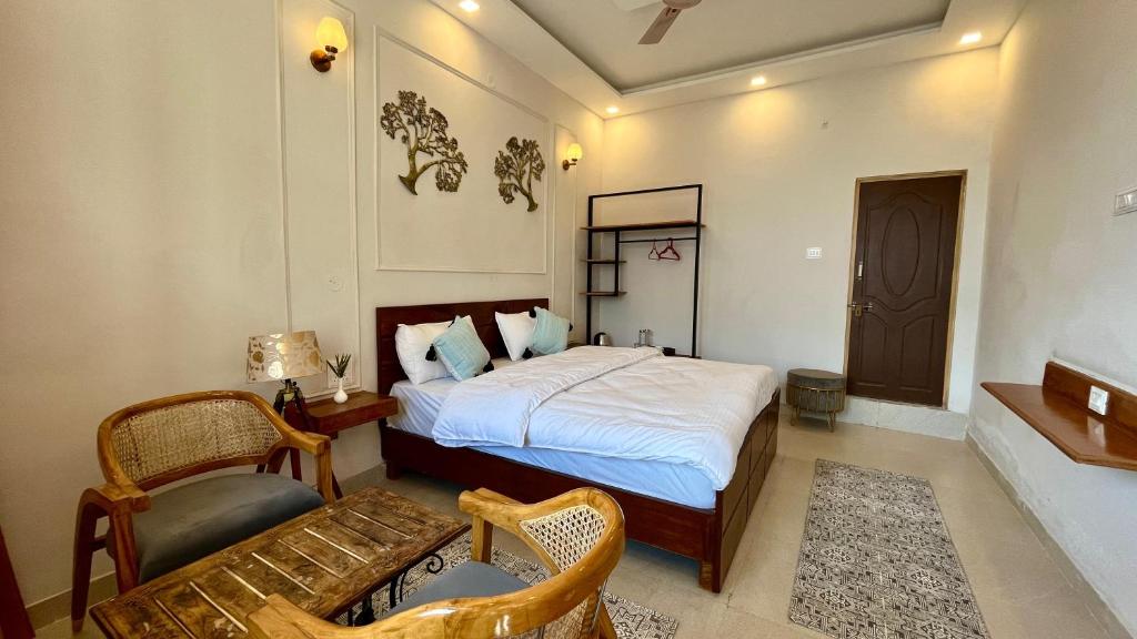 a bedroom with a bed and a chair and a table at Humming Bird By Aaryam in Ukhimath
