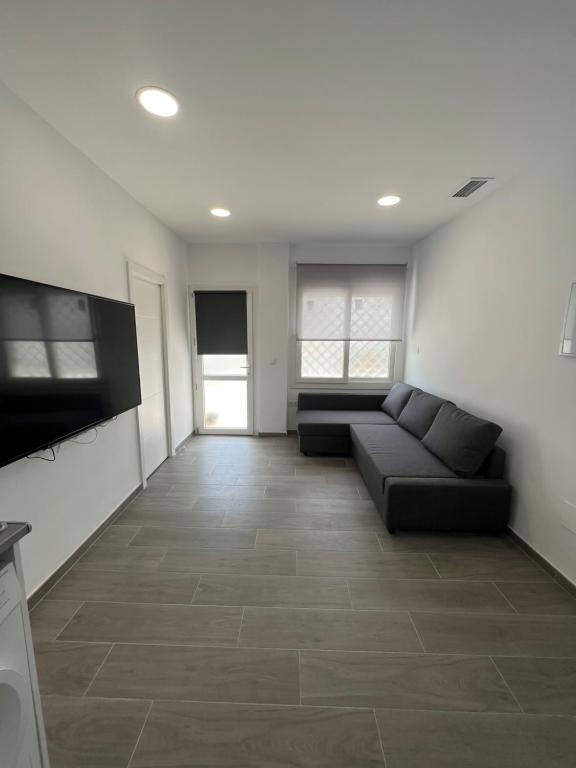 een woonkamer met een bank en een televisie bij Apartamentos BEACHYDAYS Metrópolis A in Torremolinos