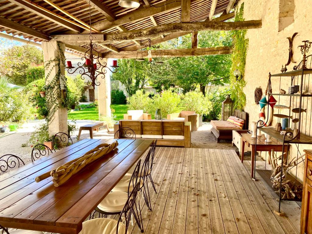 a wooden patio with a wooden table and chairs at Aux Agapanthes, Maison d'Hôtes Charentaise de Charme in Aumagne
