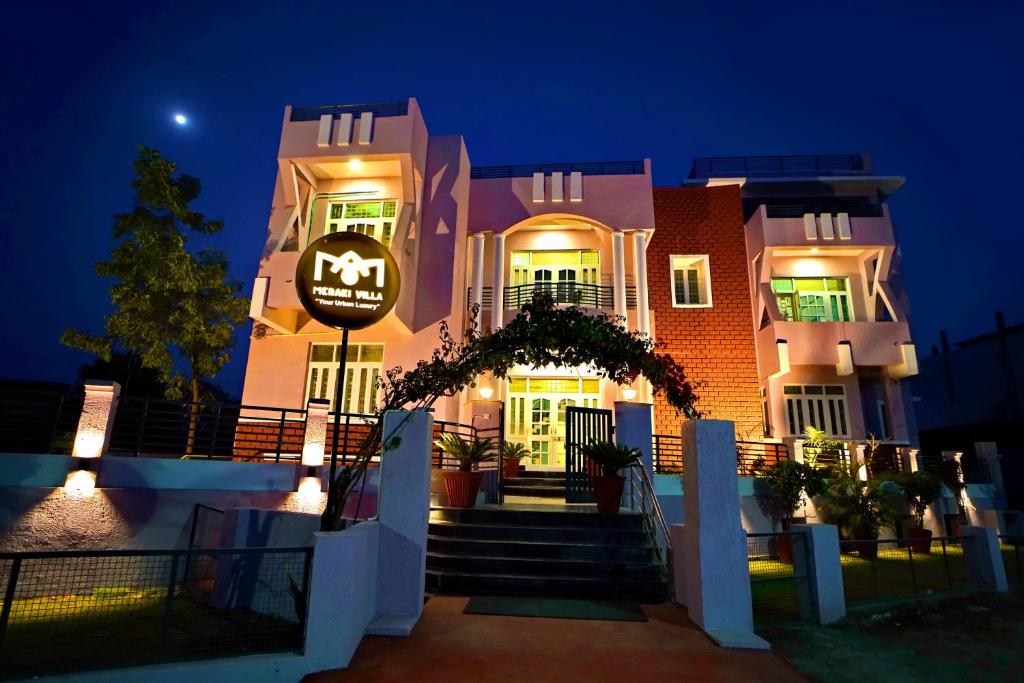 ein rosafarbenes Gebäude mit einem Schild am Abend in der Unterkunft MERAKI VILLA - 5 BR Luxury Villa with private pool in Udaipur