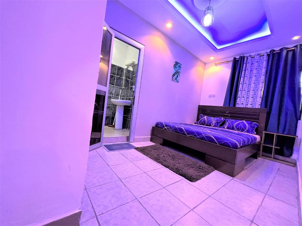 a purple room with a bed and a window at The Yafé Bastos 17 in Yaoundé