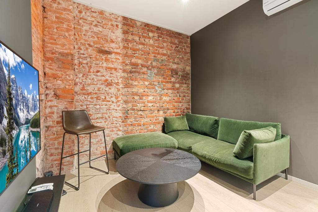 a living room with a green couch and a brick wall at Høystandard Sentral Perle in Kristiansand