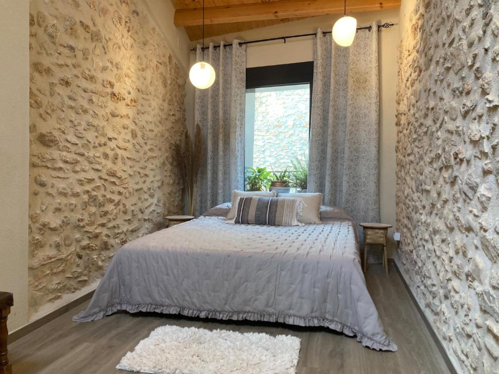 1 dormitorio con cama y pared de piedra en AltHouse Canet lo Roig, en Canet lo Roig