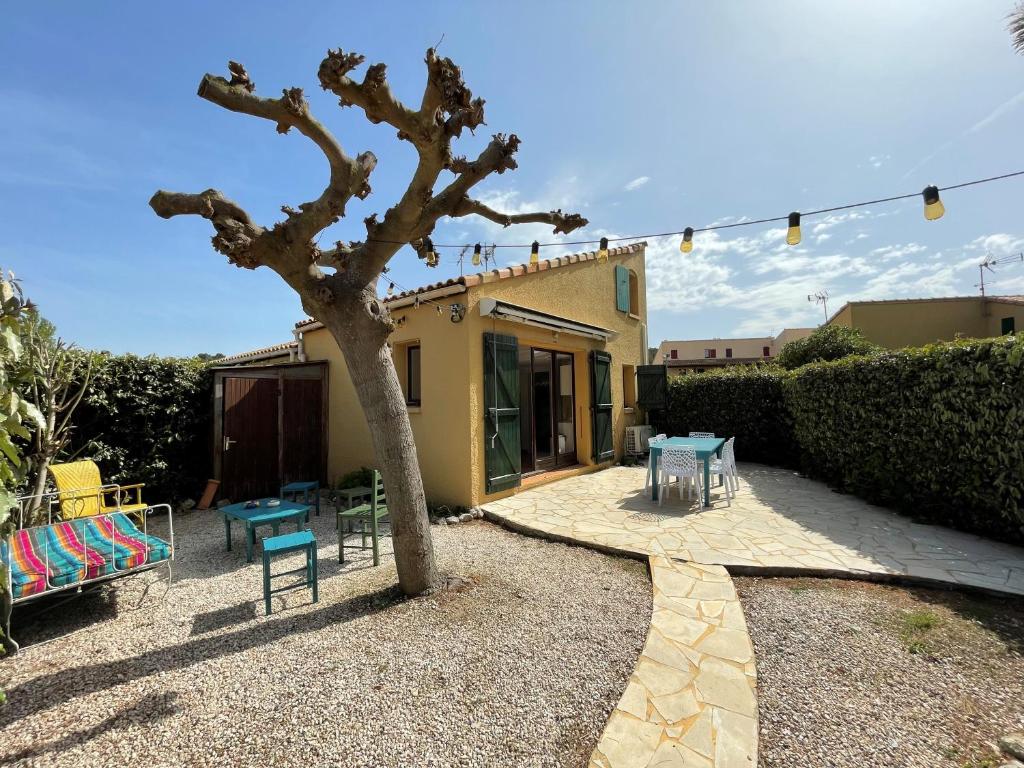 une terrasse avec un arbre, une table et des chaises dans l'établissement Maison la Franqui, à Leucate