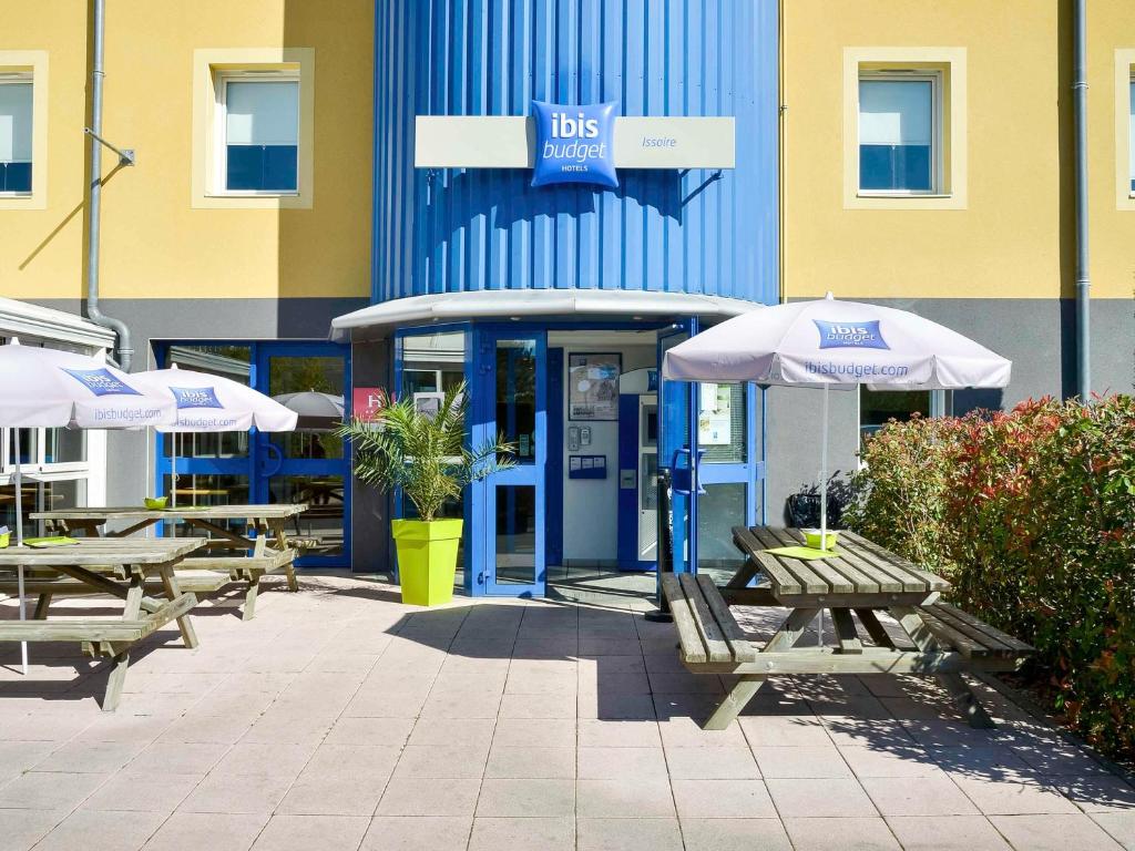 a group of tables and umbrellas in front of a building at Ibis budget Issoire in Issoire