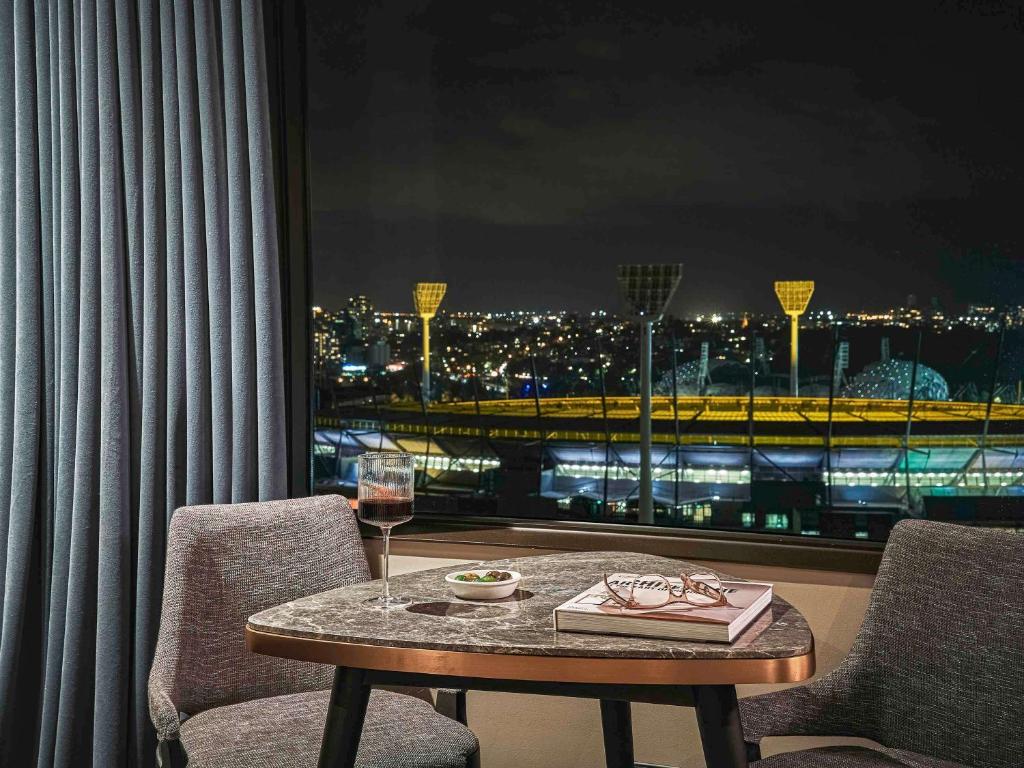 a table with a glass of wine and a window at Pullman Melbourne On the Park in Melbourne
