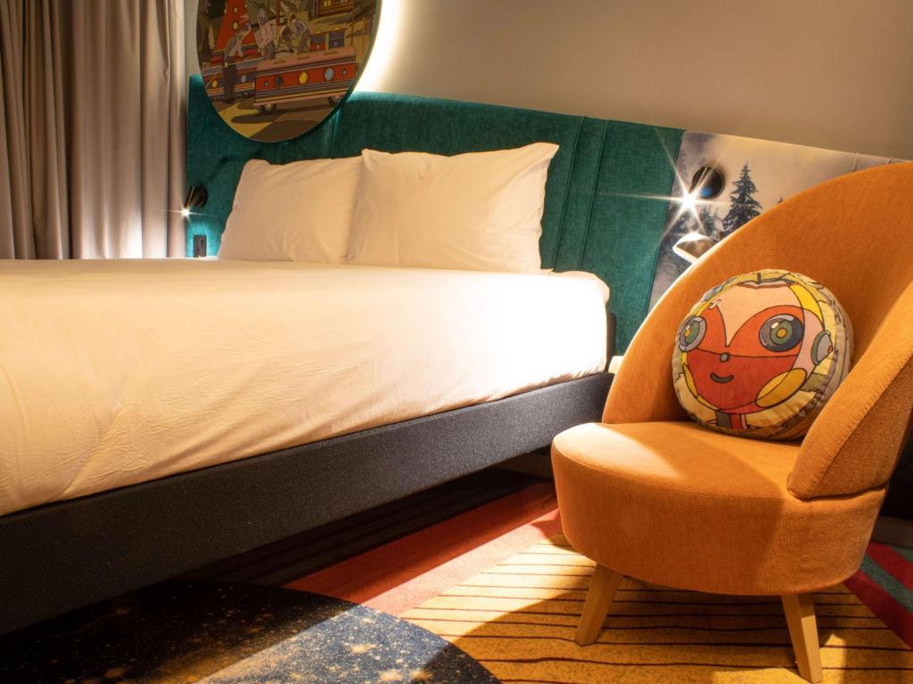1 dormitorio con 1 cama y 1 silla con almohada en ibis Styles Chelyabinsk, en Chelyabinsk
