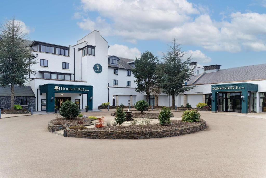 a large white building with trees in a courtyard at Doubletree by Hilton Belfast Templepatrick in Templepatrick