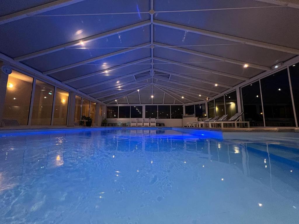 a large swimming pool with blue lighting in a building at Logis Hostellerie Du Mont Aimé in Bergères-lès-Vertus