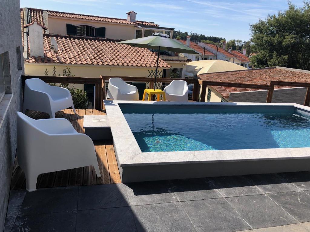 une piscine avec des chaises blanches sur le toit dans l'établissement Sun House II - Near Sintra - Kitchen - Poll, à Algueirão-Mem Martins