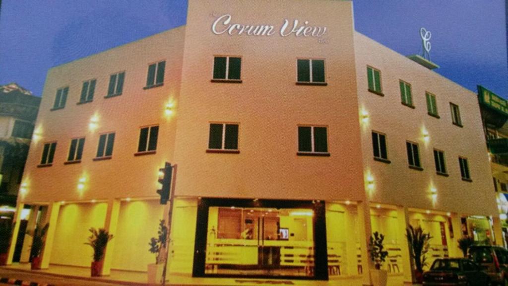 a building on the corner of a street at night at The Corum View Hotel in Bayan Lepas