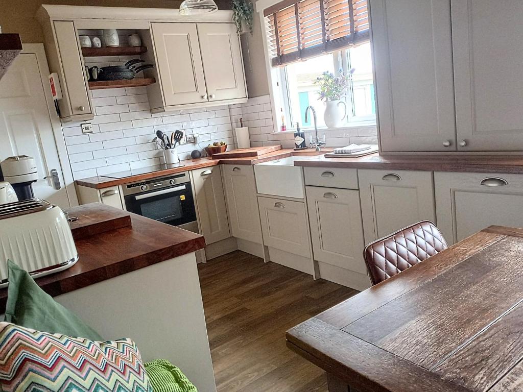 uma cozinha com armários brancos e uma mesa de madeira em Auld Tom's Rest em St. Andrews