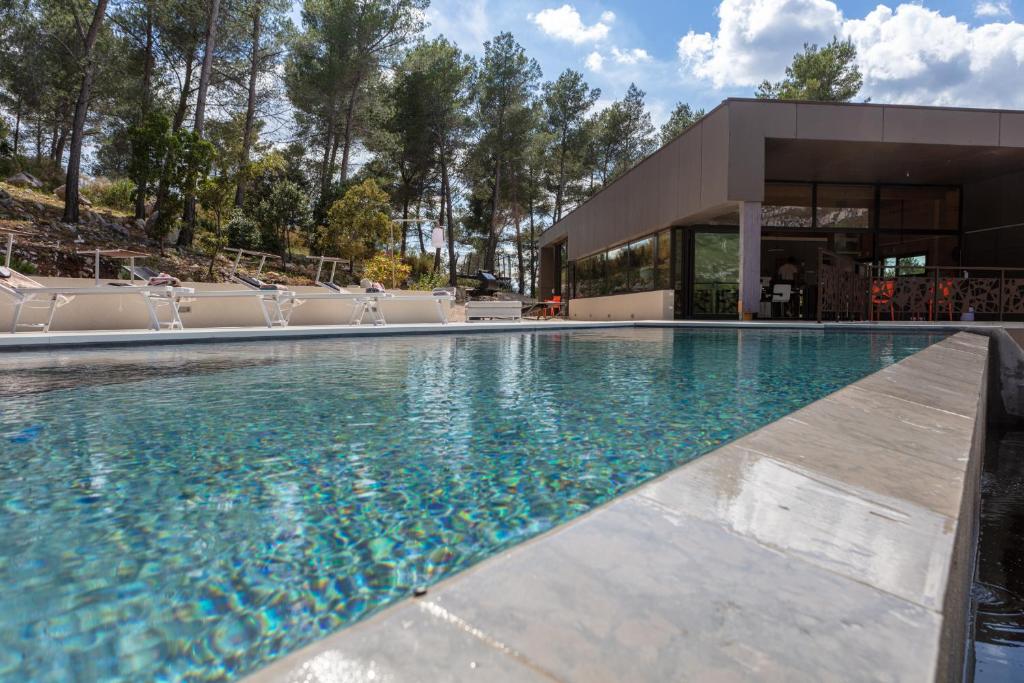 - une piscine avec des chaises en face d'un bâtiment dans l'établissement Villa Horizon 5* Piscine Jacuzzi, à Gémenos