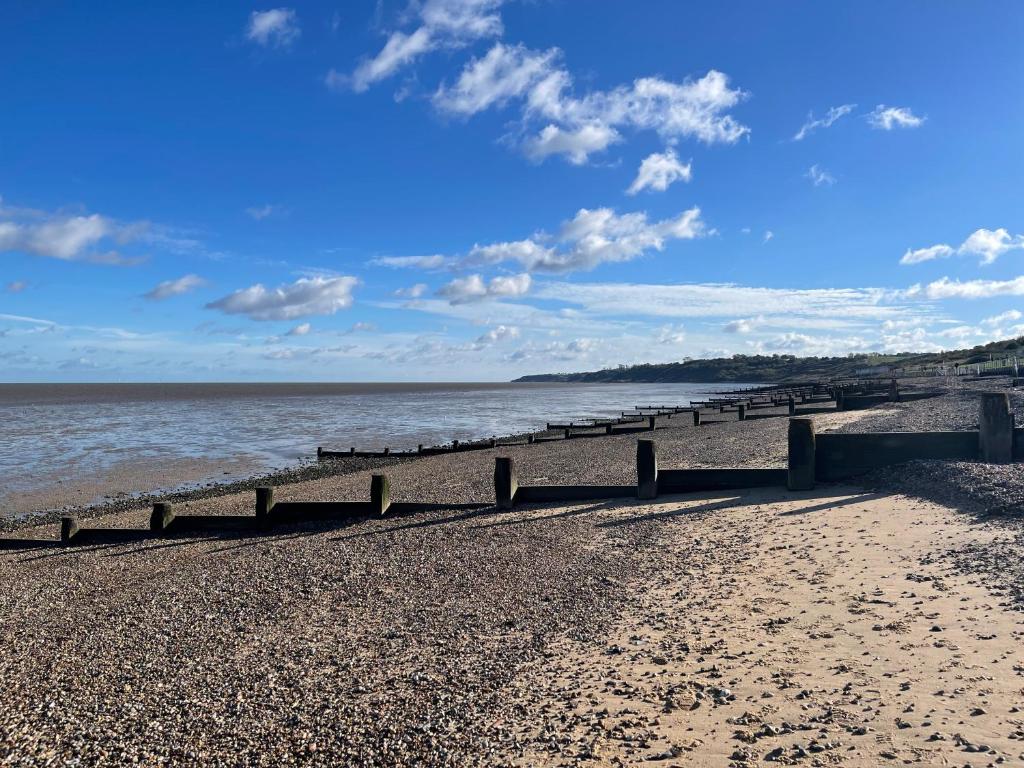 a pier on a beach with the water and clouds at Minster Leas in Sheerness