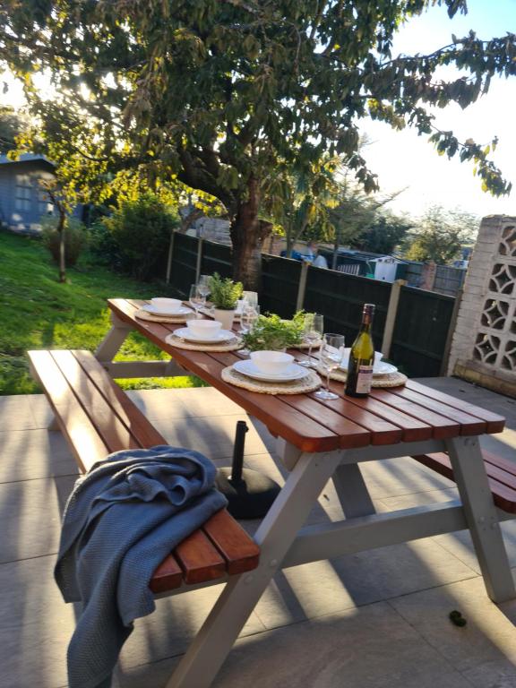 a wooden picnic table with a bottle of wine on it at Minster Leas in Sheerness