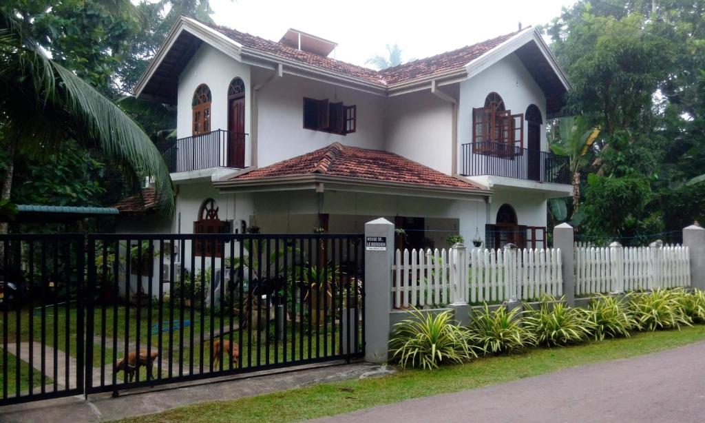 a white fence in front of a white house at Le Meridien B&B For Foreign Travelers in Negombo