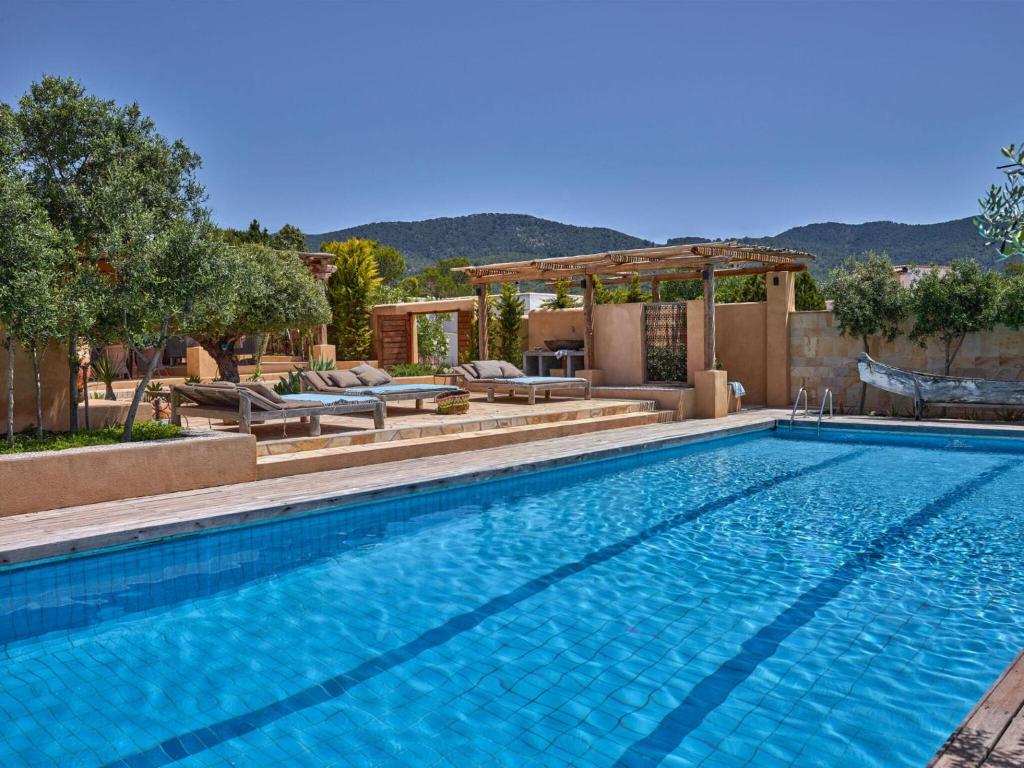 een zwembad met stoelen en een prieel bij Cozy three bedroom villa with Es Vedra views! in Cala Vadella