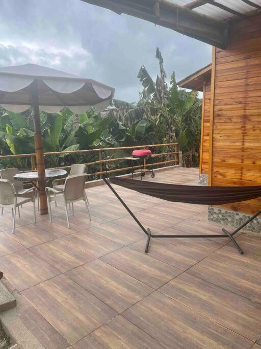a patio with a table and chairs and an umbrella at Cabaña de dos habitaciones CAPRI Eje Cafetero in Circasia