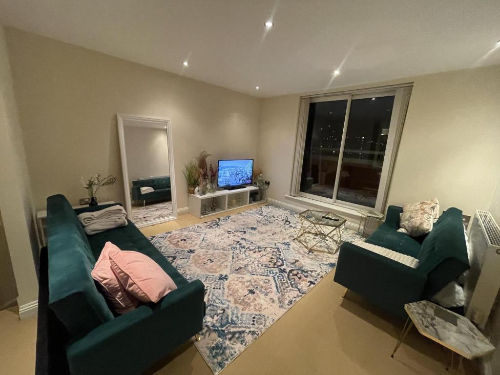 Sala de estar con 2 sofás verdes y TV en Free parking near city centre & stadium sleeps 6-8 en Leicester