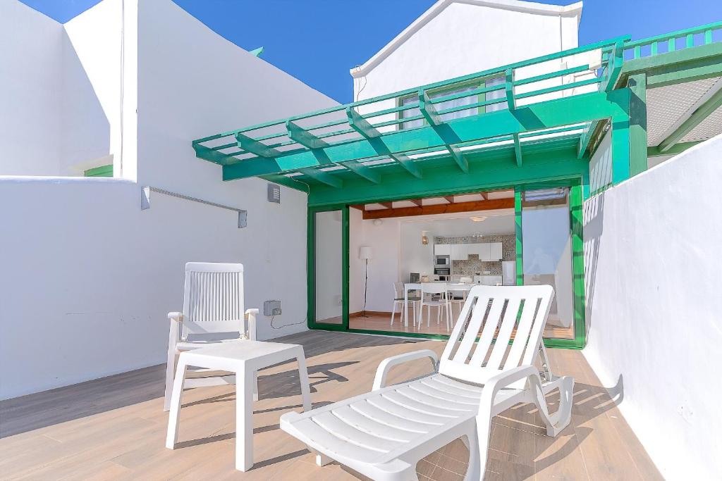 d'une terrasse avec 2 chaises blanches et un toit vert. dans l'établissement Fantástico apartamento con terraza y vistas al mar, à Costa Teguise