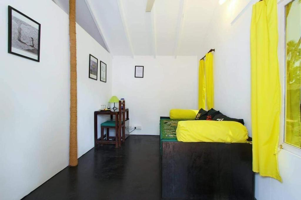 Art village resort Goa في محطة كاناكونا: غرفة نوم بسرير اصفر وطاولة