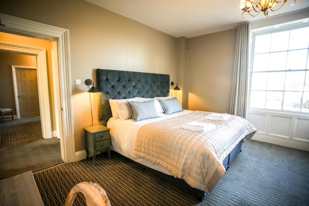 Schlafzimmer mit einem großen Bett mit blauem Kopfteil in der Unterkunft The Lazy Goose - Coffee House & Bedrooms in Stonehouse