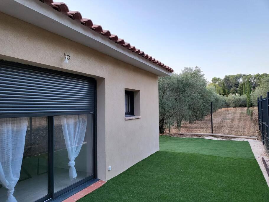 une maison avec une fenêtre et une cour avec de l'herbe verte dans l'établissement Maison jardin privatif au coeur d'une oliveraie, à Roquevaire