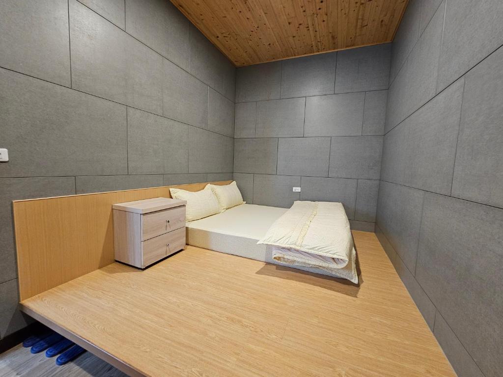 Habitación pequeña con cama y mesita de noche en 正記製茶所民宿, en Le-yeh