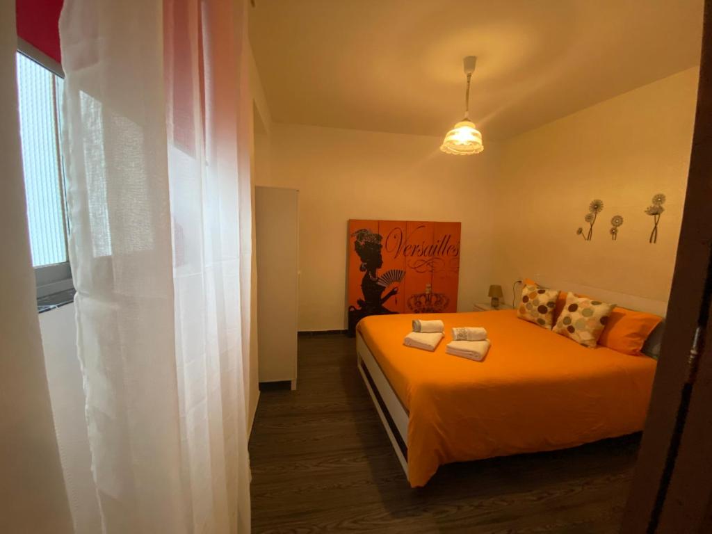 sypialnia z łóżkiem z pomarańczową pościelą i poduszkami w obiekcie Apartamento Callejon del Beso w Sewilli