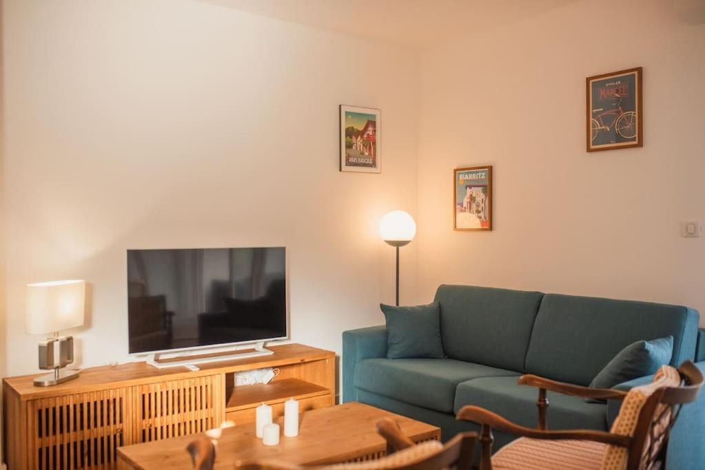 un salon avec un canapé bleu et une télévision dans l'établissement Appartement La Case, à Soorts-Hossegor