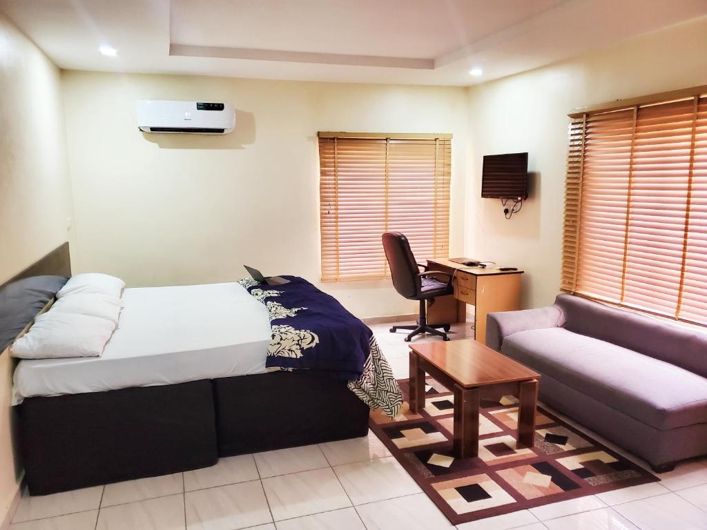 a room with a bed and a couch and a desk at Central District Apartment (Abuja) in Aso