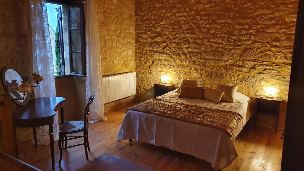 a bedroom with a bed and a table and a window at Maison Domme Dordogne in Domme