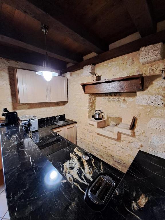 a kitchen with a counter top and a stone wall at Maison Domme Dordogne in Domme
