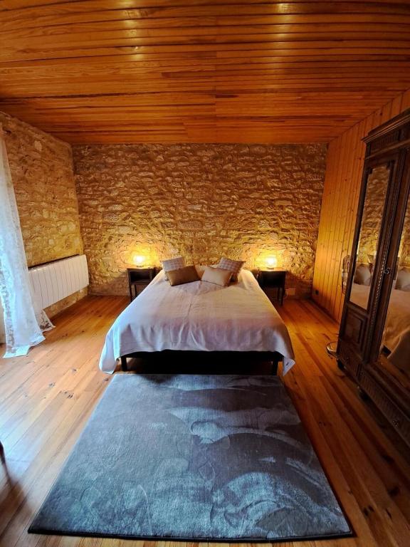 a bedroom with a large bed in a brick wall at Maison Domme Dordogne in Domme