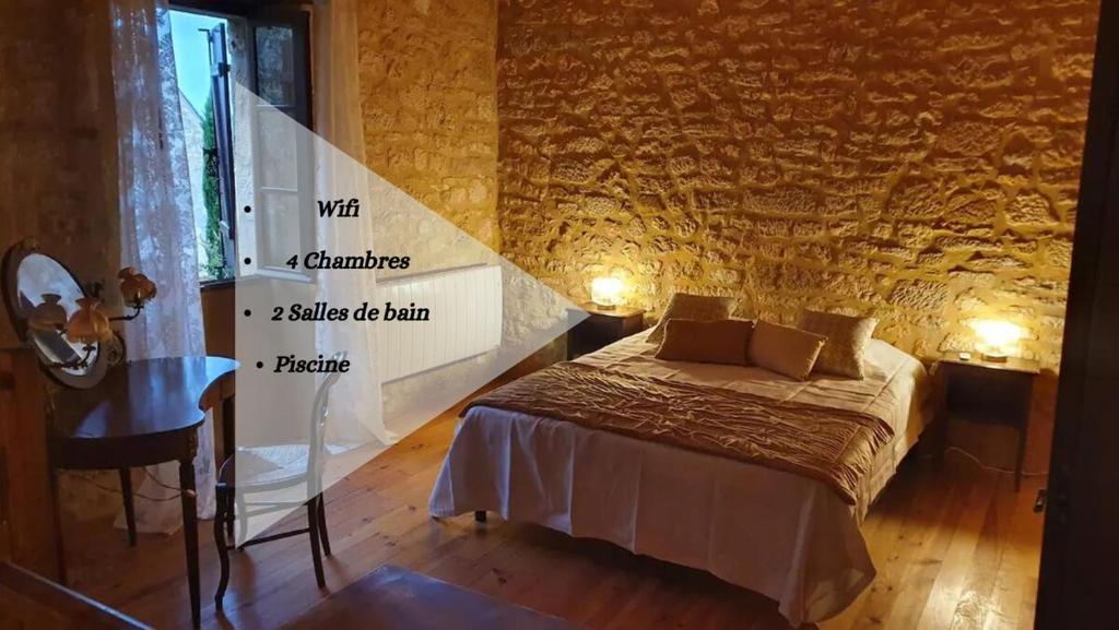 a bedroom with a bed and a stone wall at Maison Domme Dordogne in Domme