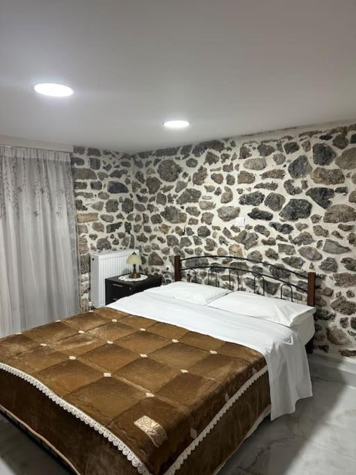 1 dormitorio con 1 cama grande y pared de piedra en Lovely Apartment in Litoxoro en Litóchoron
