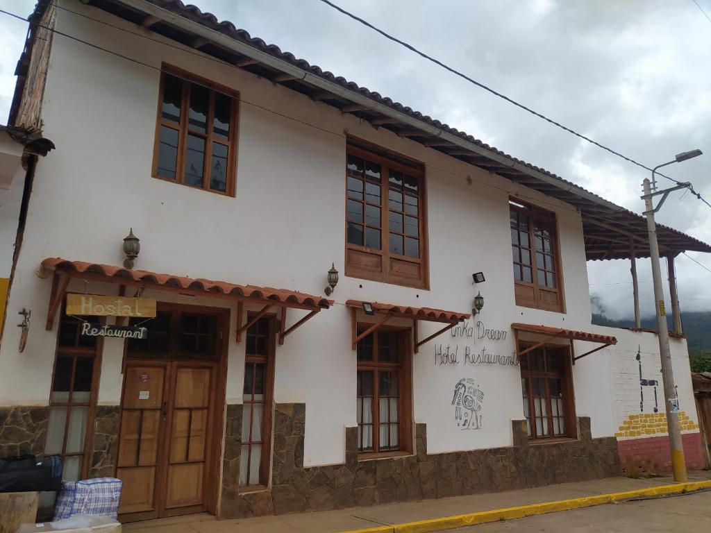 - un bâtiment blanc avec des portes et des fenêtres en bois dans l'établissement Inka Dream, à Cachora