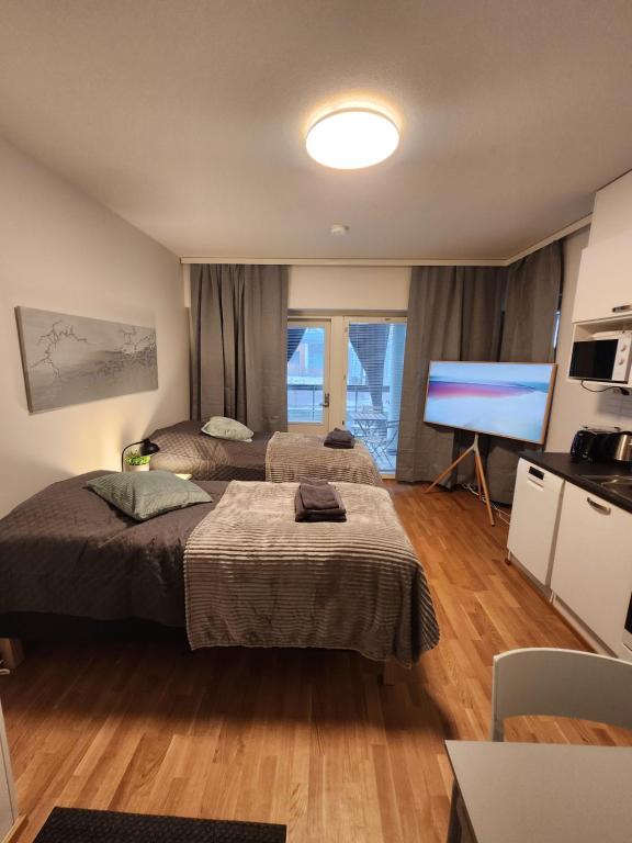 a bedroom with two beds and a flat screen tv at Viihtyisä täysin kalustettu ja varustettu yksiö Logomolla 1vrk-36kk in Turku
