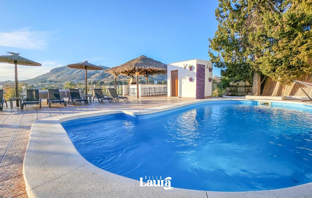 a large swimming pool with chairs and umbrellas at Villa Laura in Alhaurín el Grande