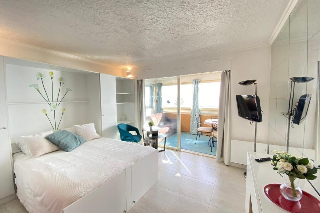 a bedroom with a white bed and a living room at 06BH - Beautiful seafront studio in Saint-Laurent-du-Var