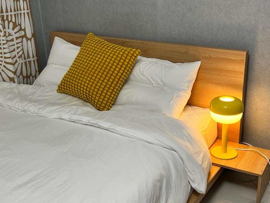 Bett mit gelbem Kissen und gelber Lampe in der Unterkunft Masil in Seoul